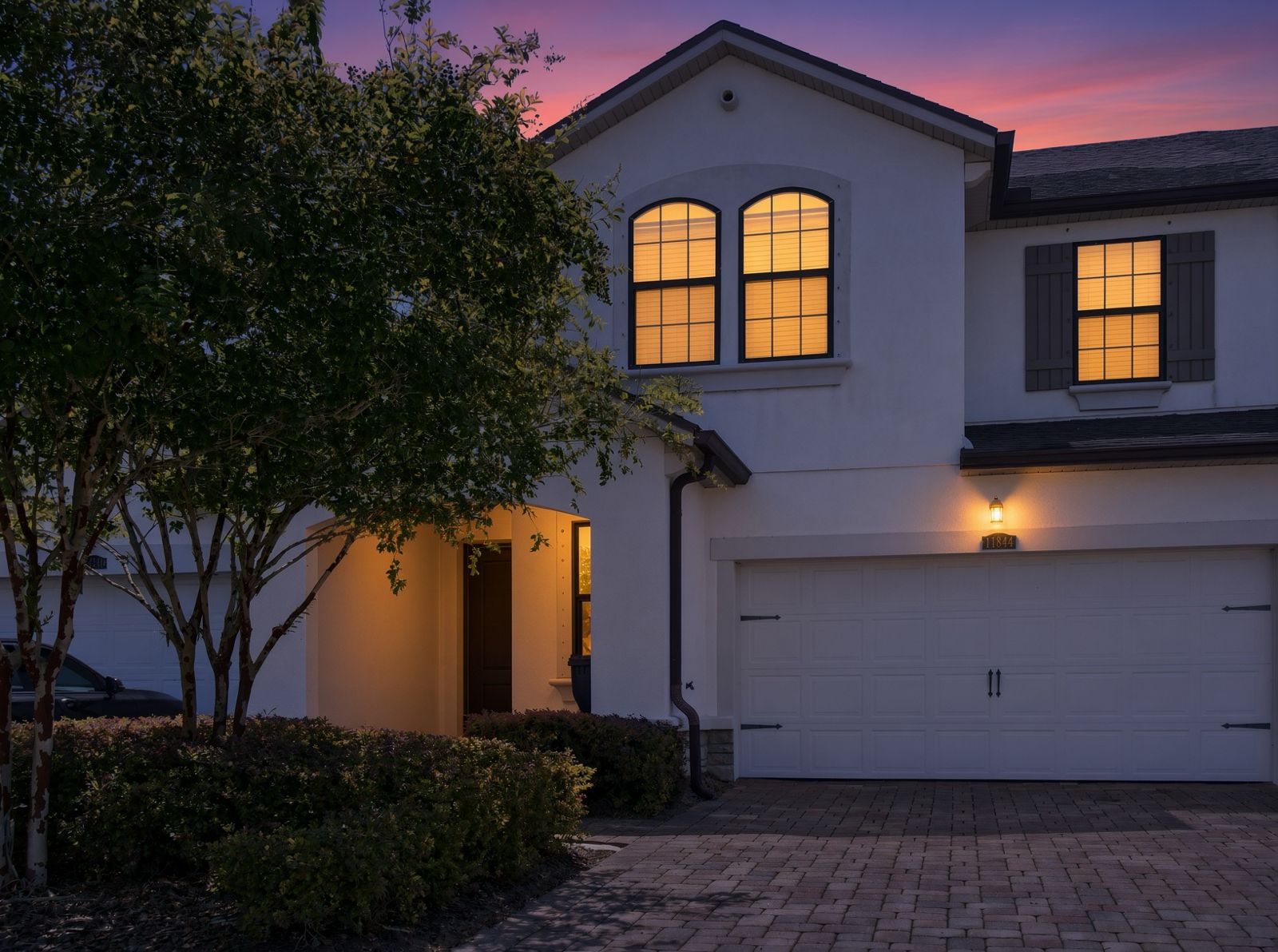 South Florida home exterior at twilight with warm interior glow